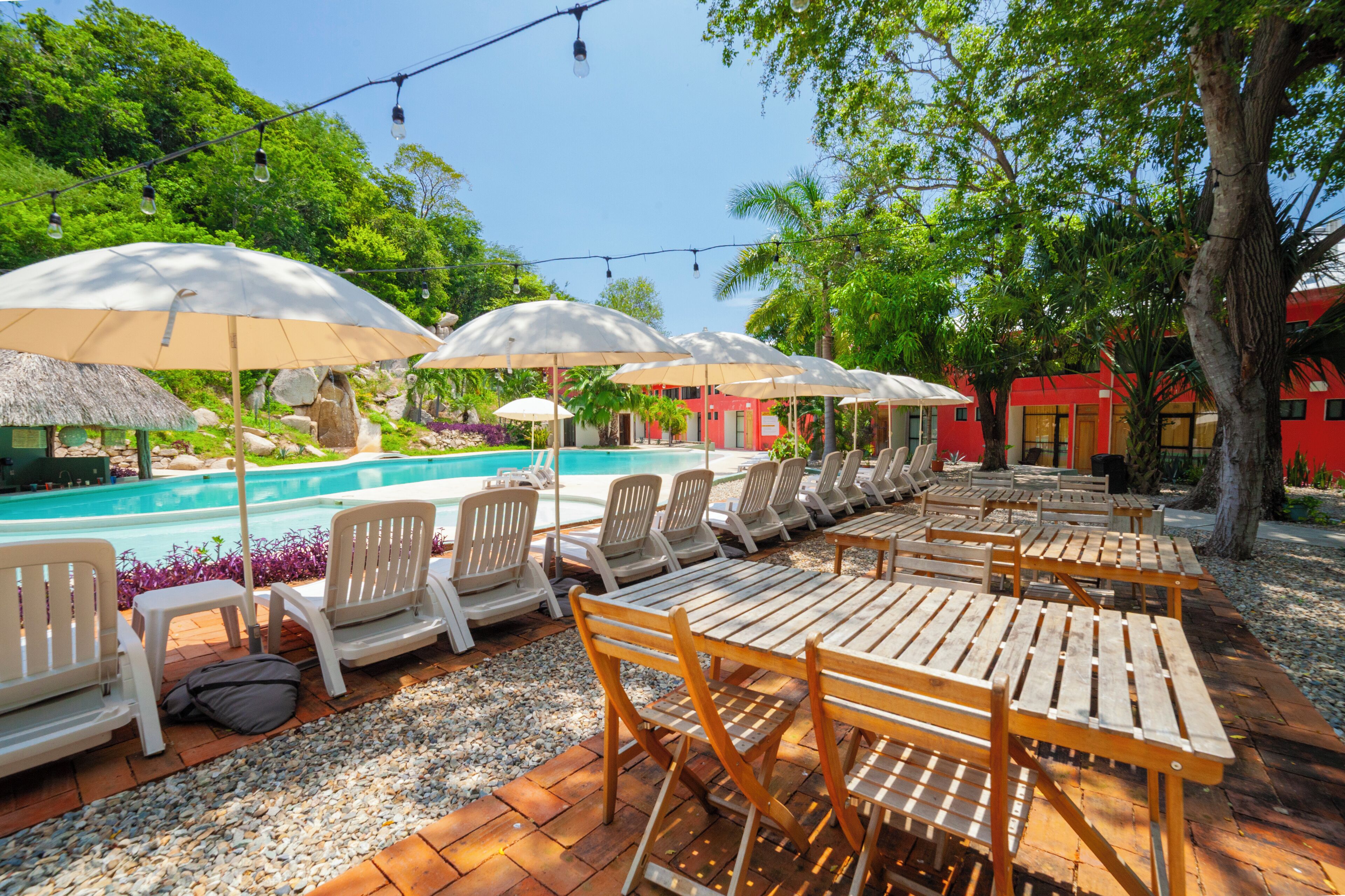 A poolside area with lounge chairs and tables, umbrellas, and a pool.