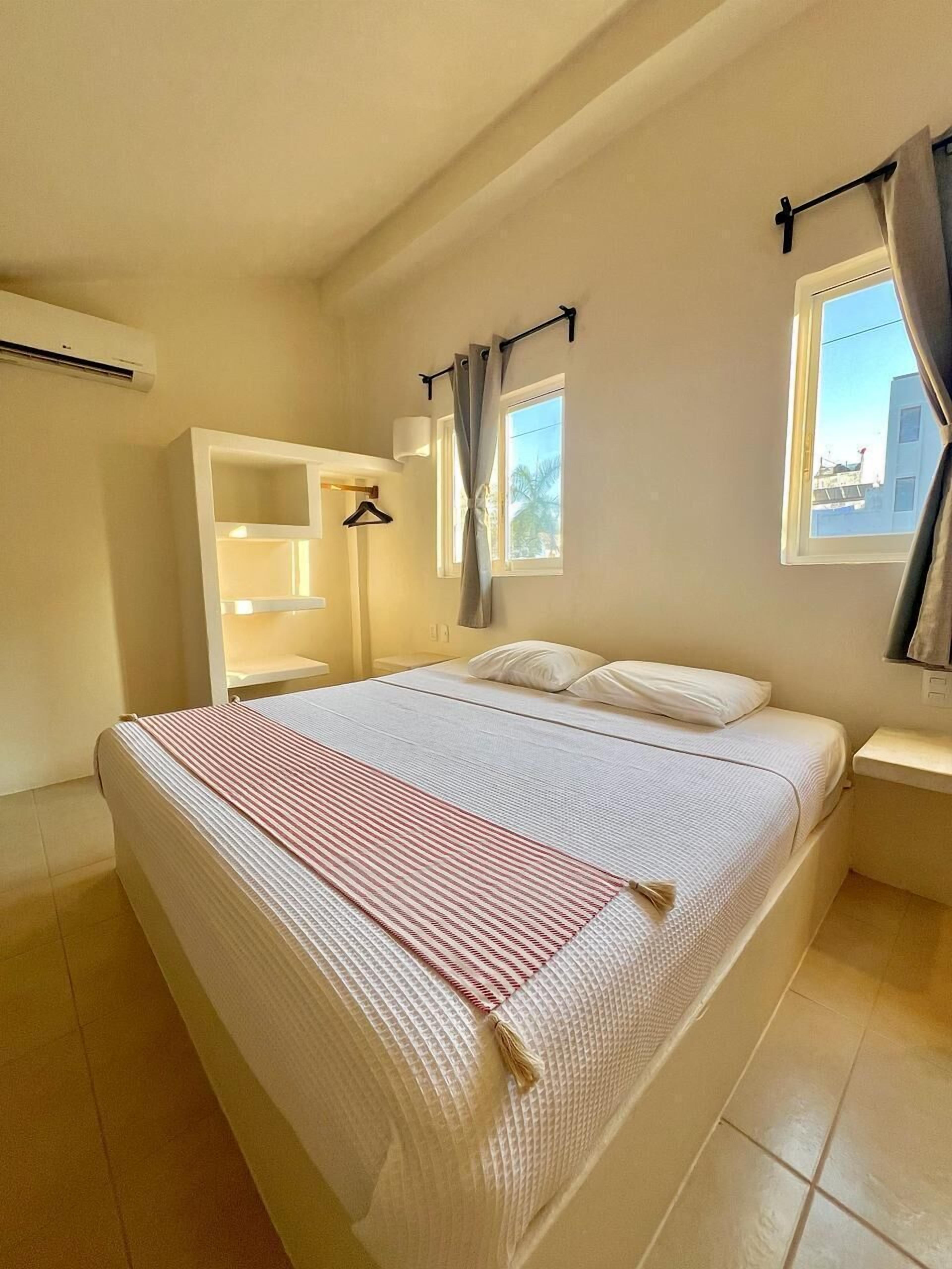 Une chambre bien rangée, avec un lit, une armoire, une table de chevet et une fenêtre avec des rideaux.