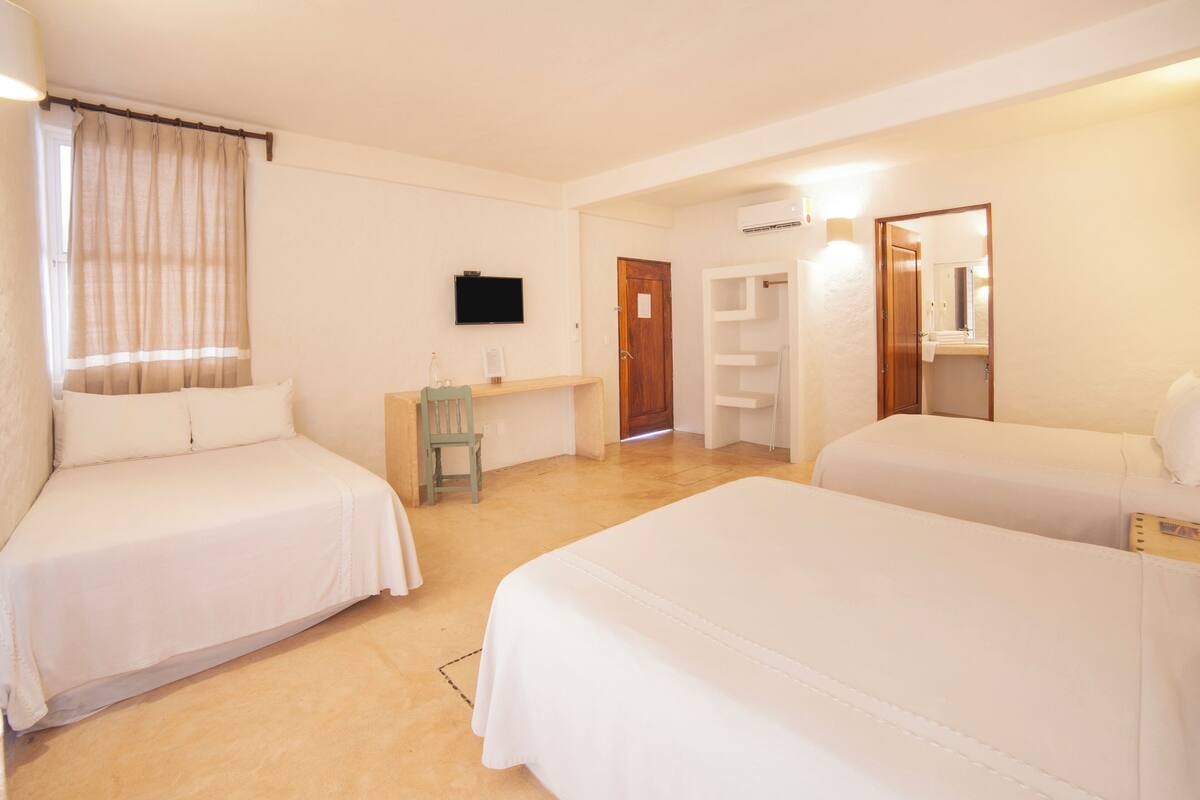 A hotel room with two beds, a TV, a desk, a chair, and a wardrobe.