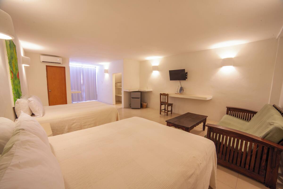 A hotel room with two beds, a desk, a chair, a television, and a window with curtains.