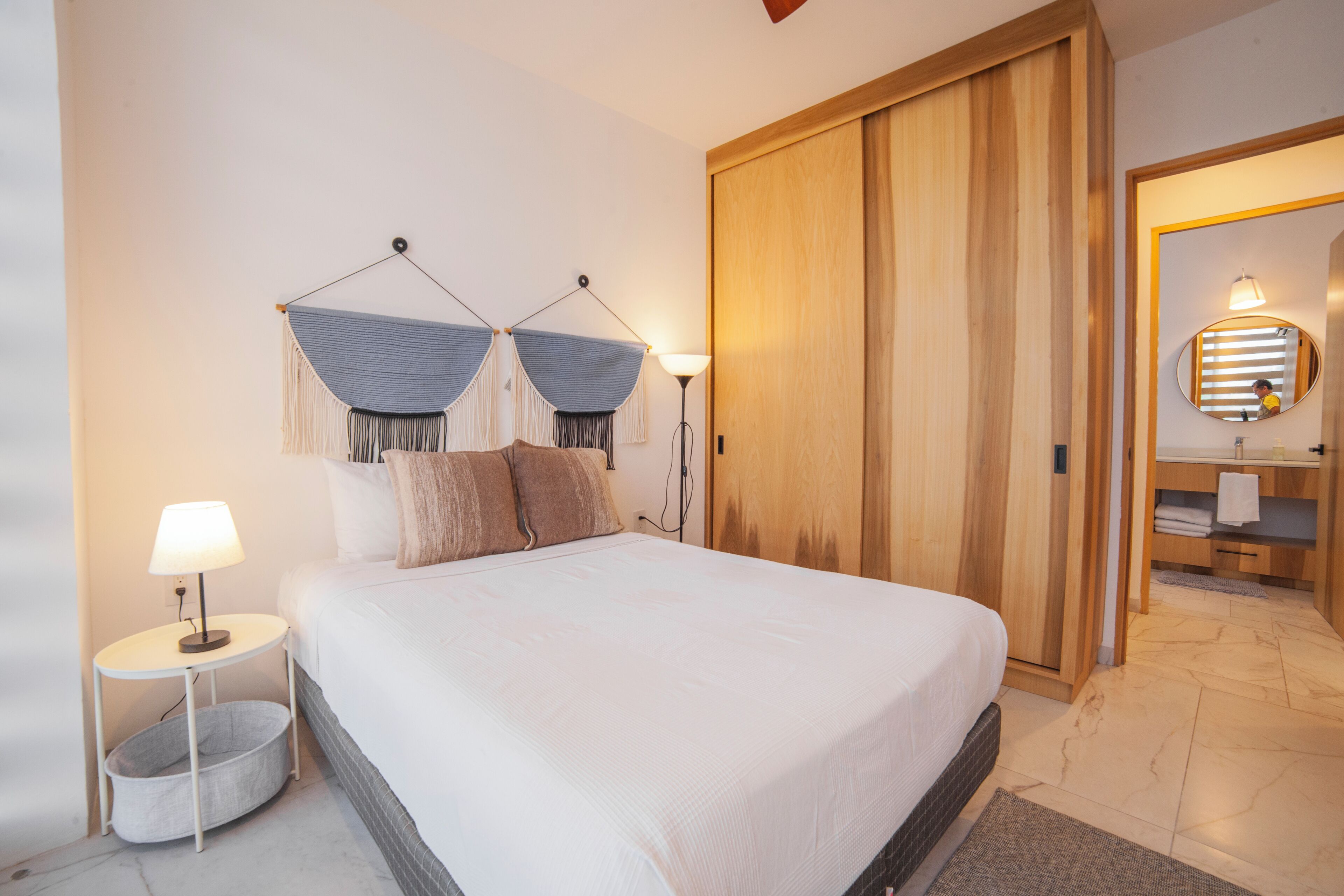 A neatly arranged bedroom with a large bed, bedside lamp, and a wooden wardrobe.