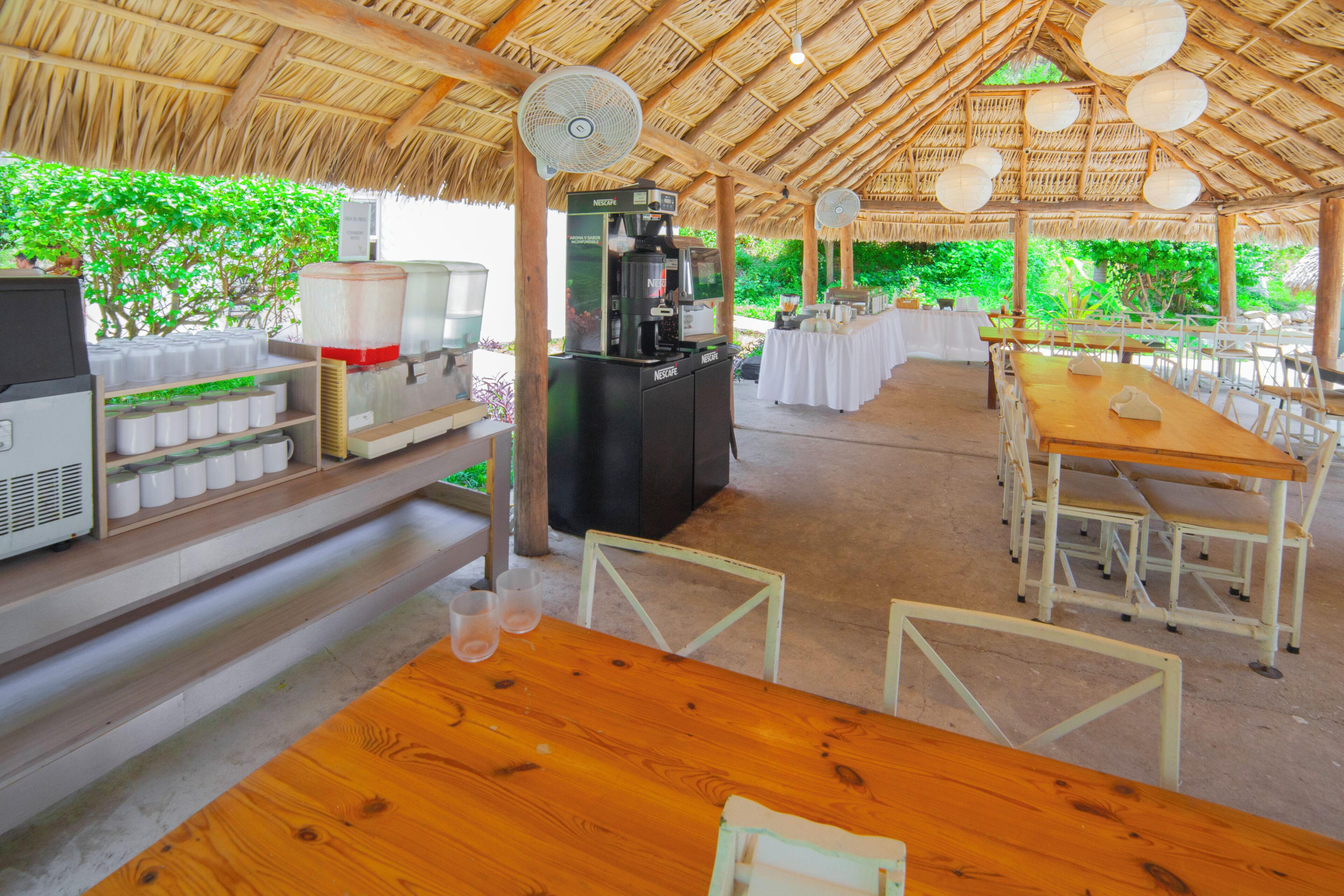 Un espace extérieur abrité, aménagé pour prendre les repas, avec un coin café, des tables et des chaises.
