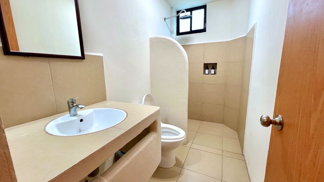 Un baño con lavamanos, inodoro y zona de ducha.