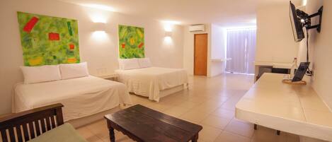 A hotel room with two beds, a wooden table, a TV, and artwork on the walls.