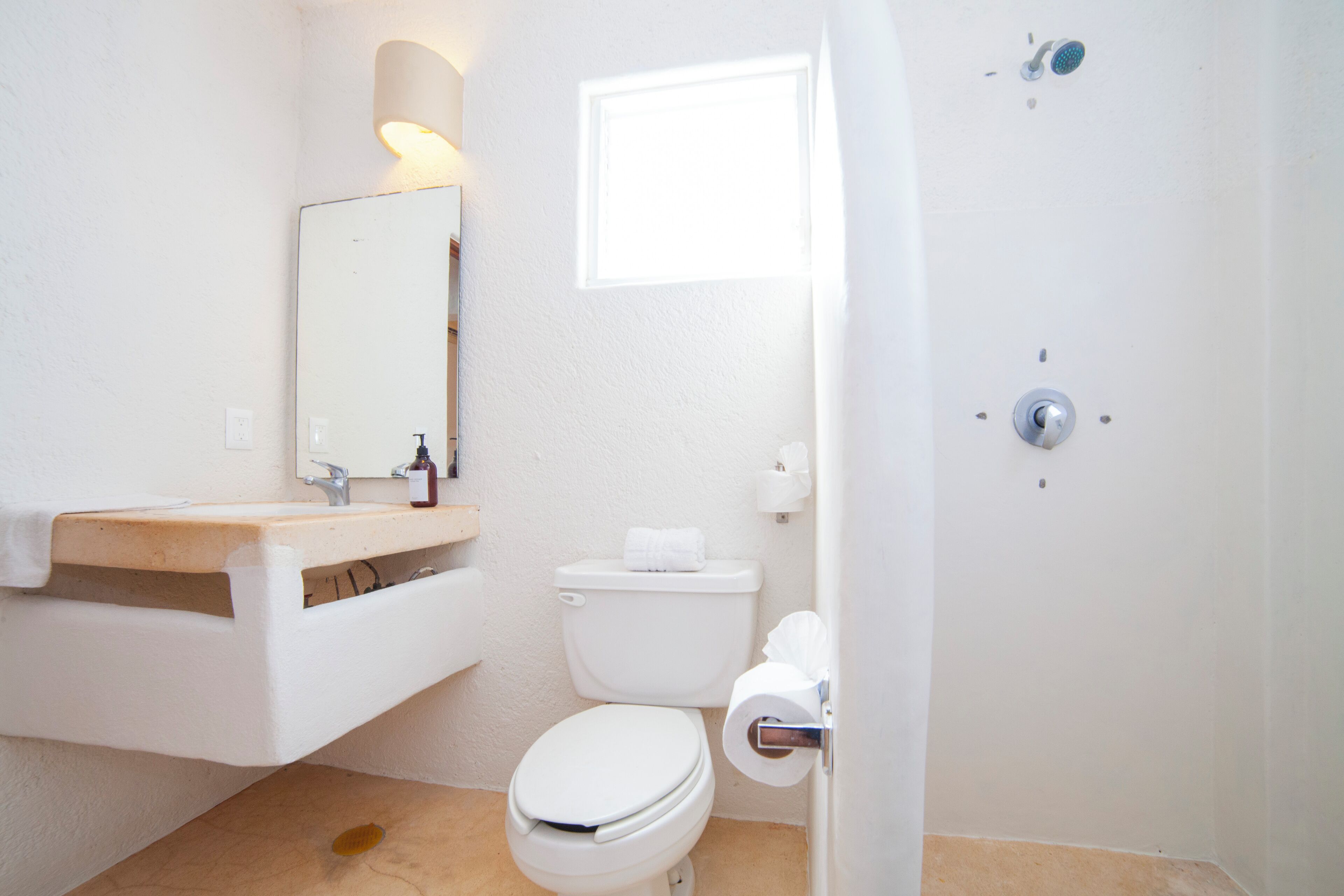 A bathroom with a toilet, sink, mirror, and shower.