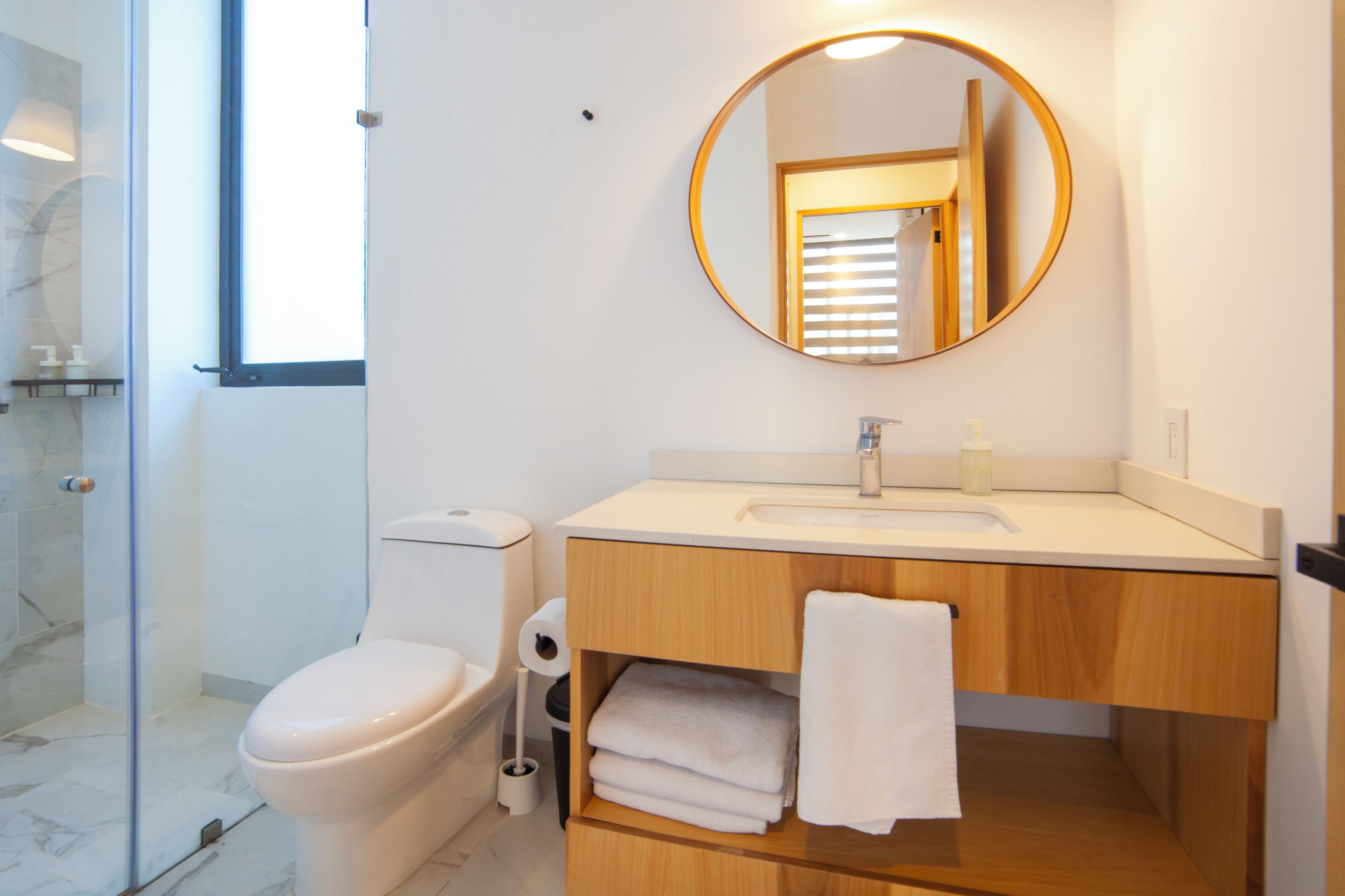 Un baño moderno con inodoro, lavamanos y espejo.