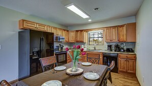Una cocina moderna con armarios de madera, una mesa de comedor preparada para cuatro personas y un florero con flores.