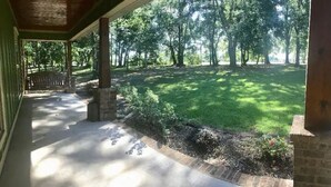 Eine überdachte Terrasse mit Blick auf eine Rasenfläche und Bäume.