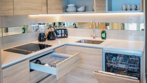 Een moderne keuken met houten kastjes, een inbouwvaatwasser, een spoelbak en een aanrecht met diverse apparaten.