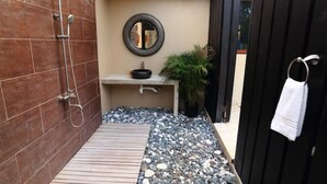 A compact bathroom with a shower, sink, and a small mirror. - Adehya the Villa (Duncans)