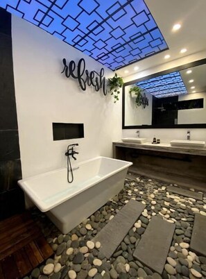 Une salle de bain moderne avec une baignoire sur pieds, un grand miroir et un mur décoratif orné du mot « rafraîchir ».