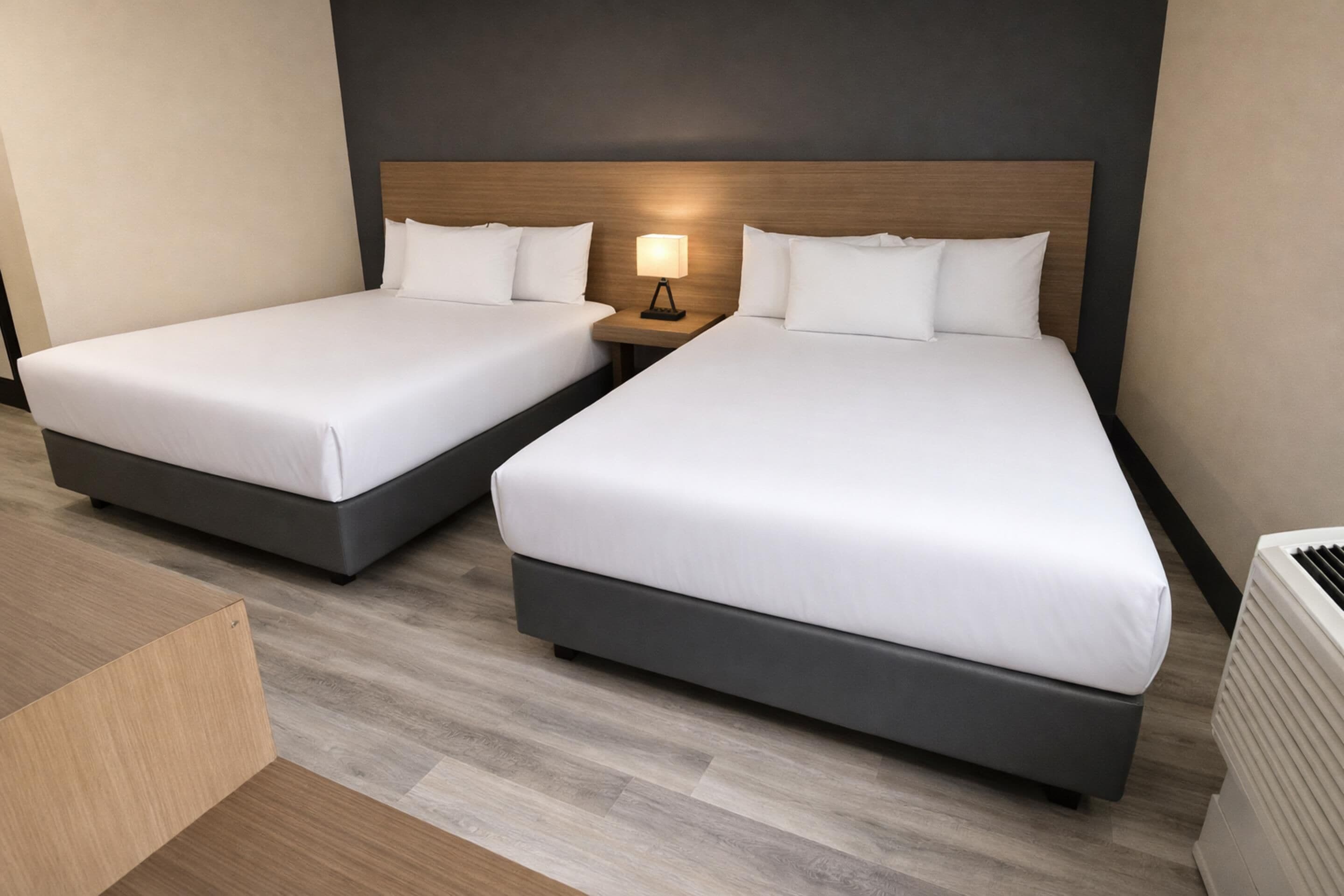 Two single beds with wooden headboards, a bedside table with a lamp, and a radiator.