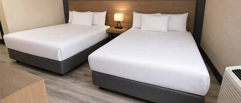 Two single beds with wooden headboards, a bedside table with a lamp, and a radiator.