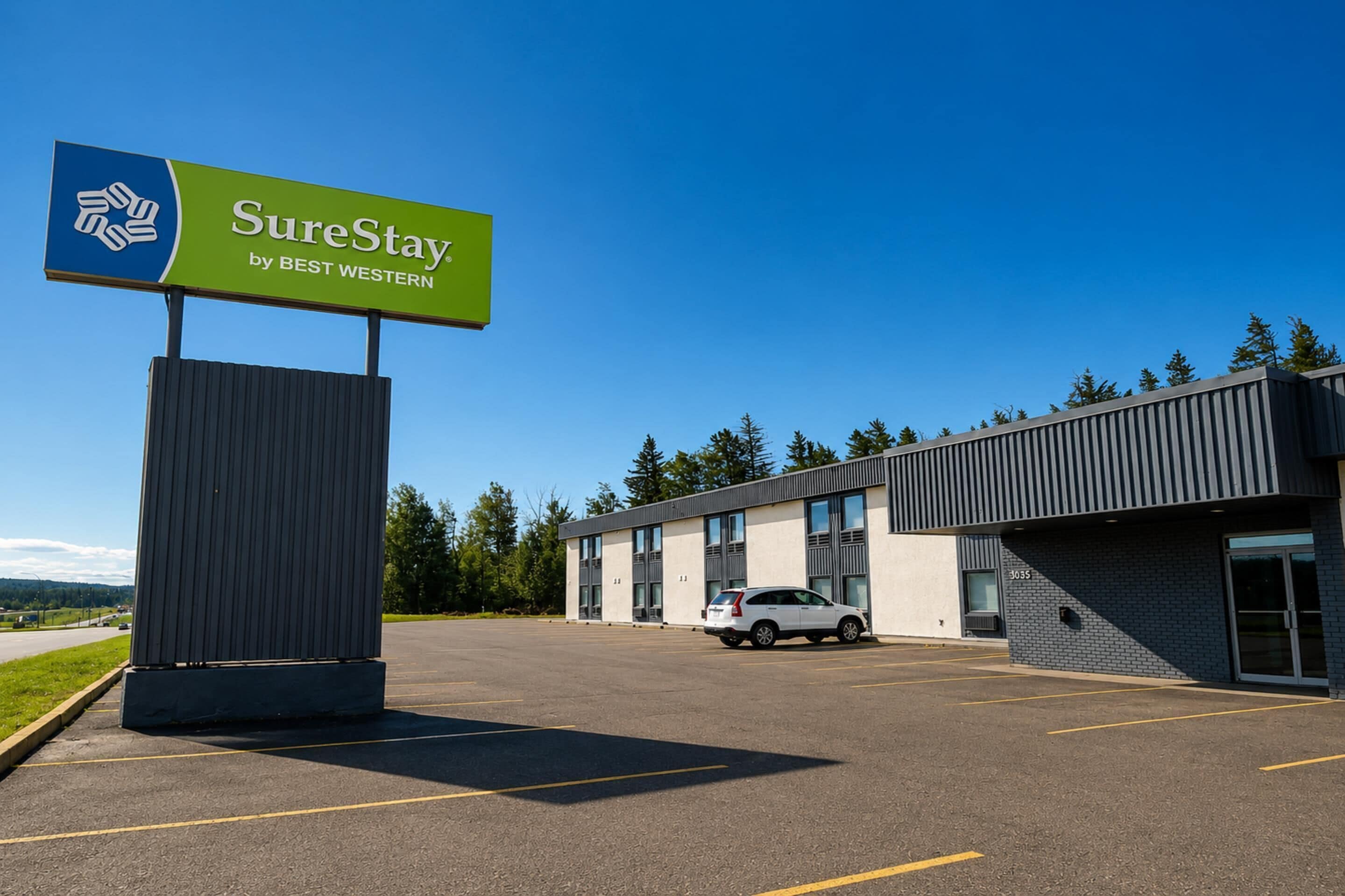 A SureStay by Best Western hotel with a parking lot and a building with large windows.