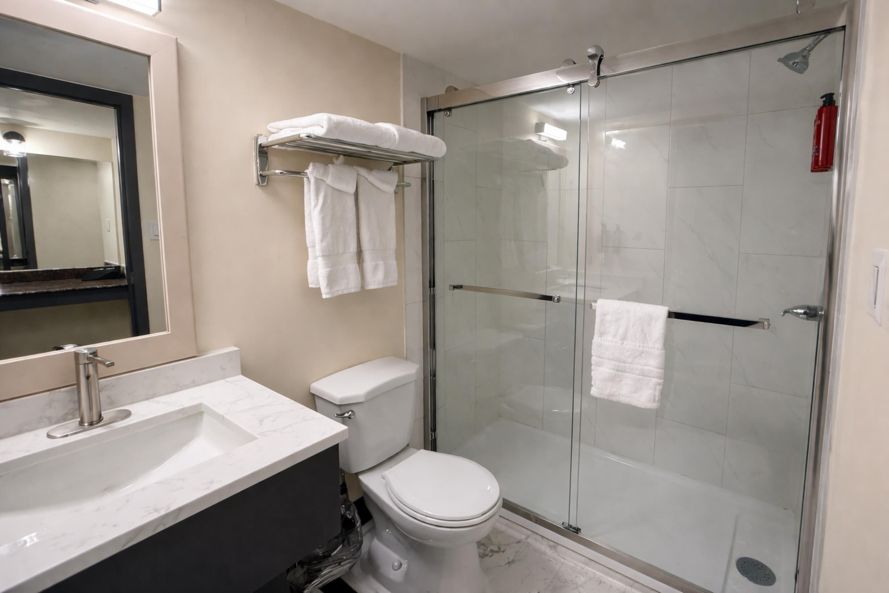 Une salle de bain moderne avec une douche à parois de verre, des toilettes blanches et un lavabo en marbre.