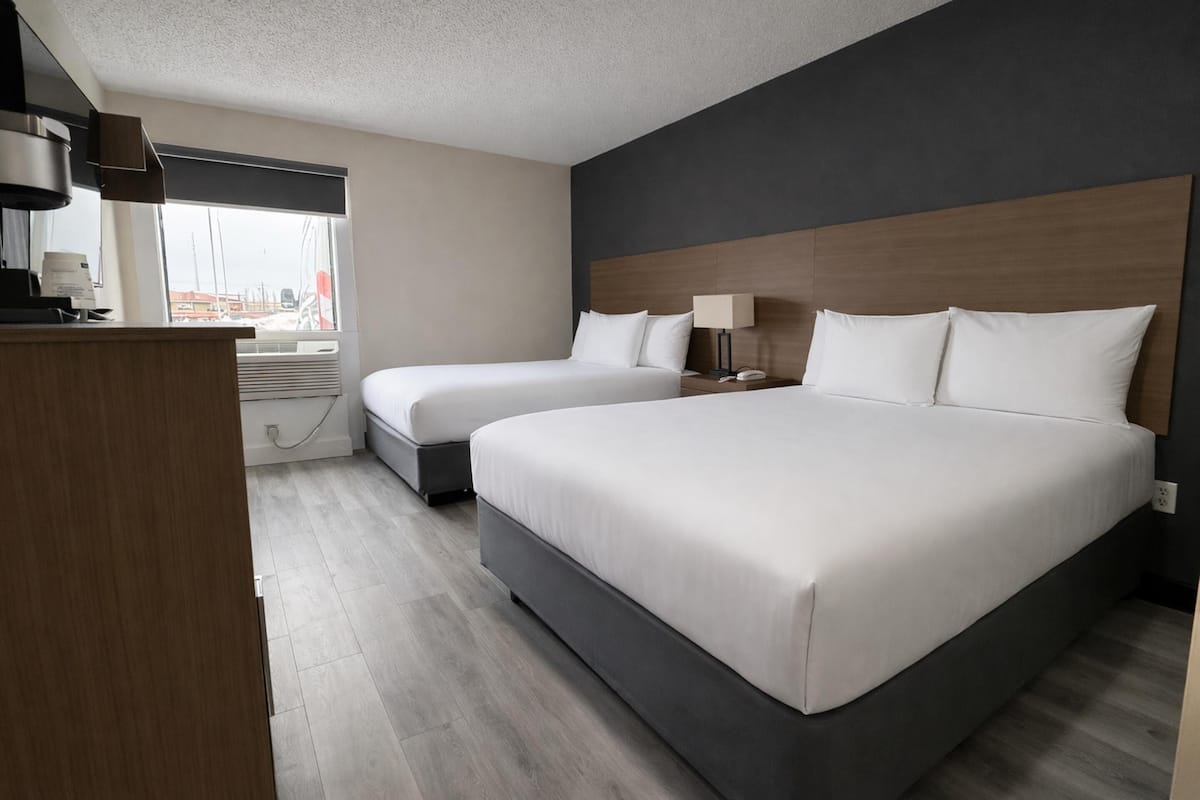 Une chambre d’hôtel avec deux lits, un bureau, une lampe et une fenêtre donnant sur un paysage agréable.