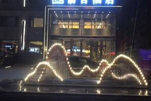 A hotel entrance with a modern design, featuring a double-story structure and a well-lit facade.