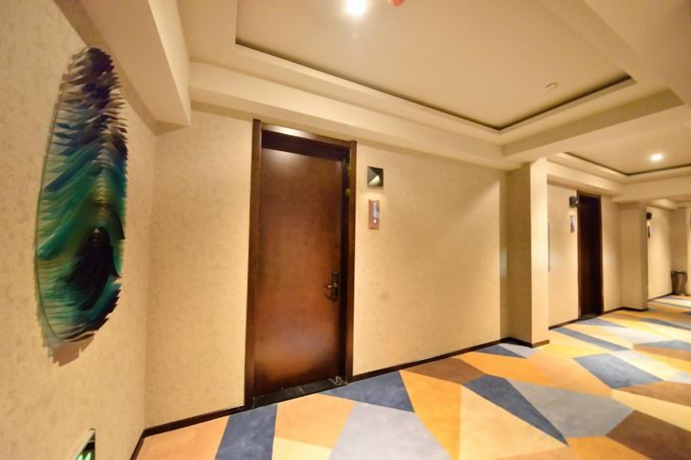 A hotel corridor with a patterned floor, a door, and a wall-mounted artwork.