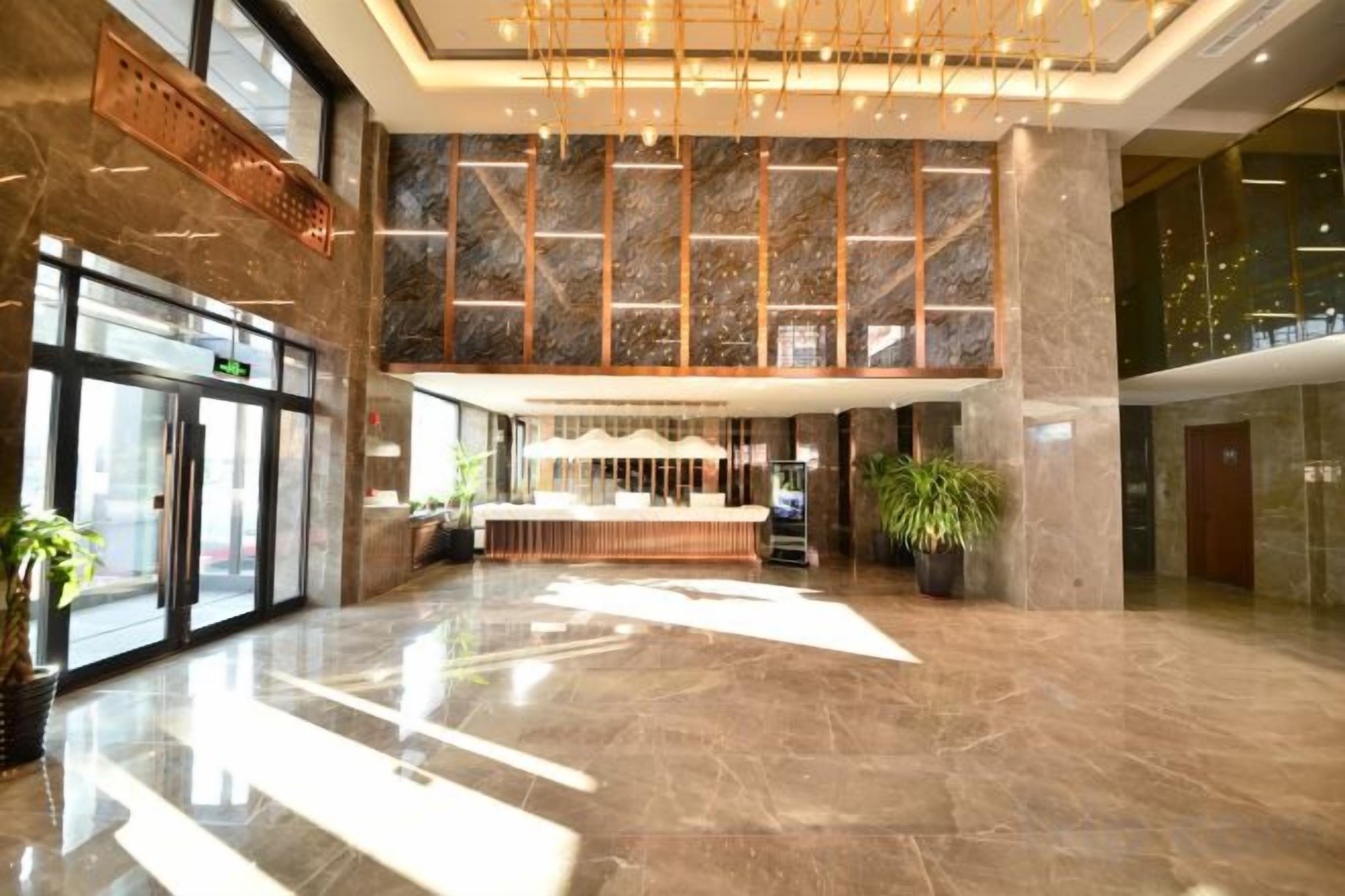 A spacious lobby with a reception desk, large windows, and a high ceiling.