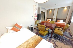 A hotel room with a large bed, a desk, two chairs, a TV, and a mirror. - Lanshe Hotel (Harbin)