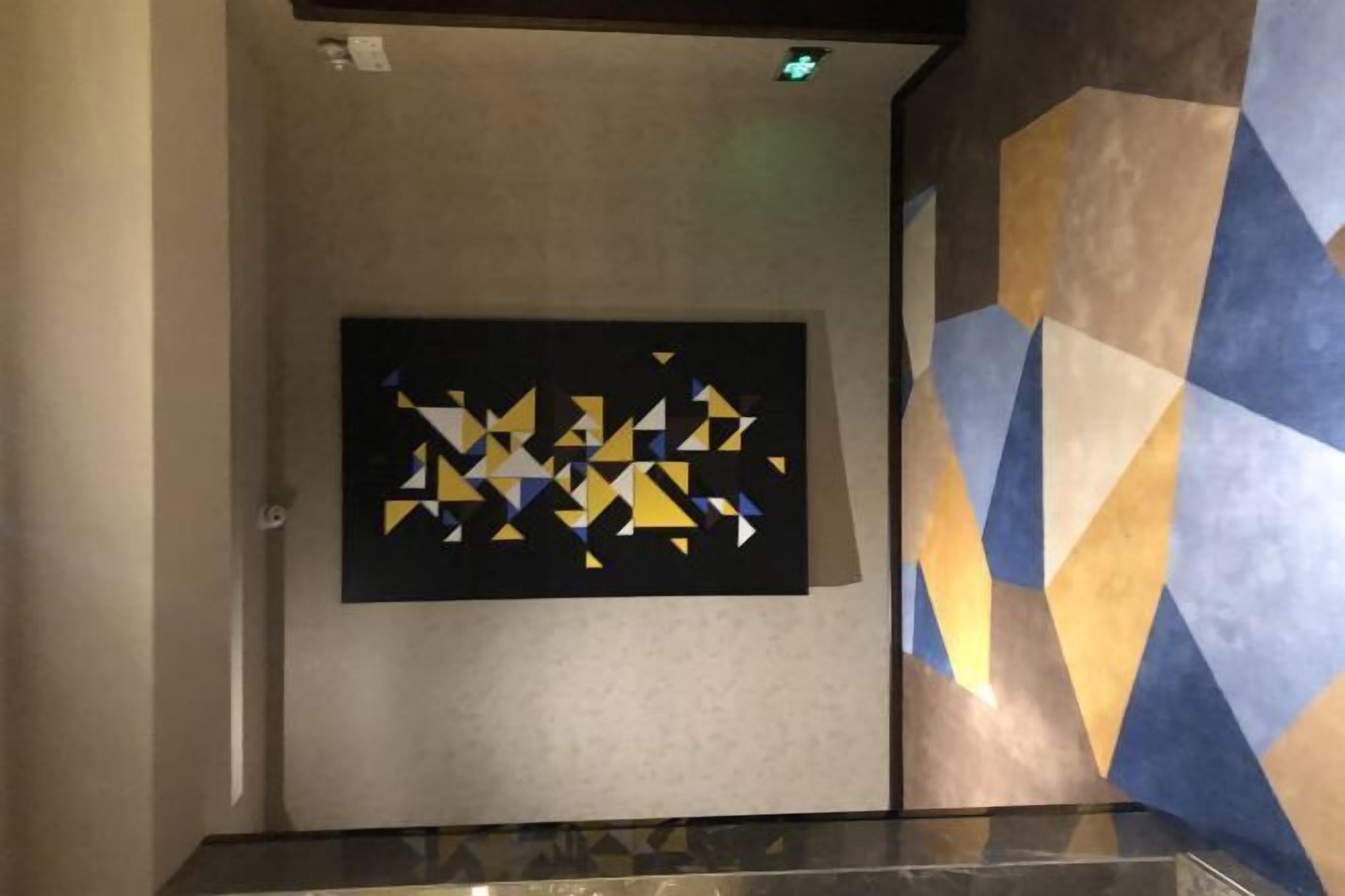 A hallway with a geometric patterned wall and a framed artwork on the wall.