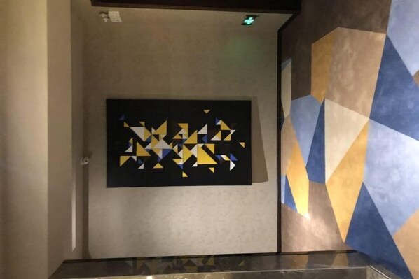 A hallway with a geometric patterned wall and a framed artwork on the wall. - Lanshe Hotel (Harbin)