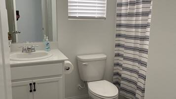 A bathroom with a white sink, mirror, toilet, and striped shower curtain.