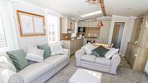 A spacious living area with two sofas, a coffee table, and a kitchen in the background.