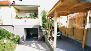 A covered outdoor area with a wooden pergola, a small table, and chairs. - Apartment Ana Zadar (Zadar)
