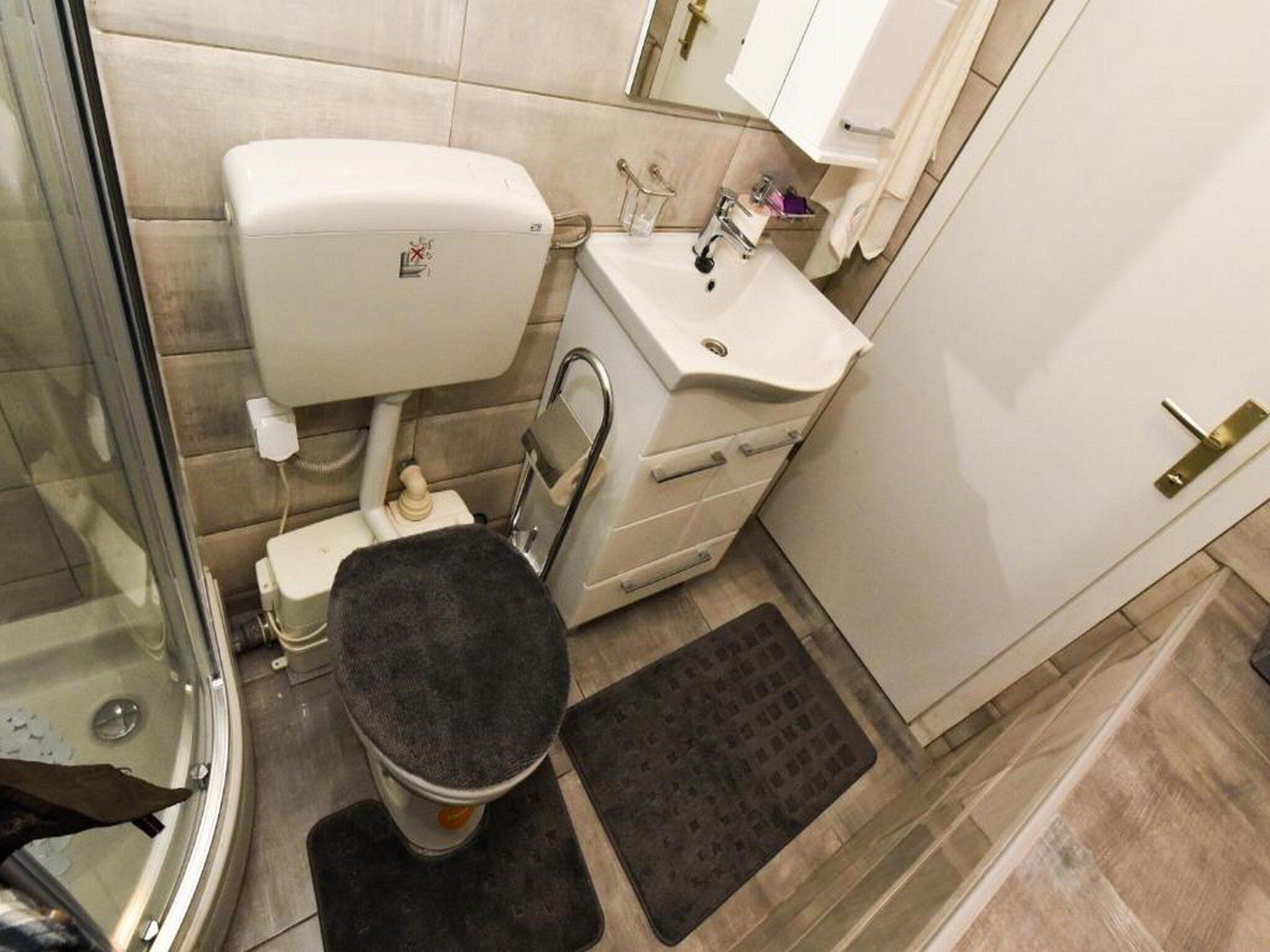 A compact bathroom with a toilet, sink, and shower.