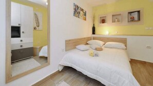 A bedroom with a bed, a large mirror, a TV, and a shelf with decorative items. - Apartment Ana Zadar (Zadar)