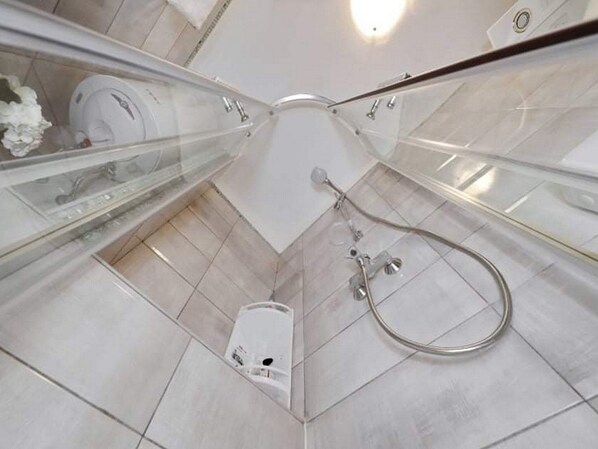 Uma casa de banho moderna com chuveiro em cabine de vidro, sanita e banheira.