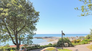 A coastal view with a mosaic bench, a tree, and a clear sky. - Coram Cottage (Lyme Regis)