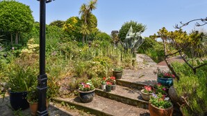 A garden with various potted plants and a stone staircase. - Coram Cottage (Lyme Regis)