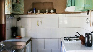 A kitchen with white tiles, a gas stove, a coffee maker, and a shelf with various kitchen items. - Sage House - One Bedroom Holiday Cottage with Terrace (Trpanj)