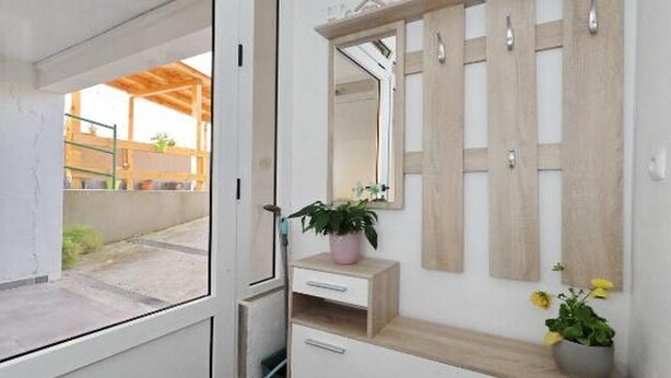 Une salle de bain moderne avec un grand miroir, un meuble-lavabo en bois et une plante en pot.