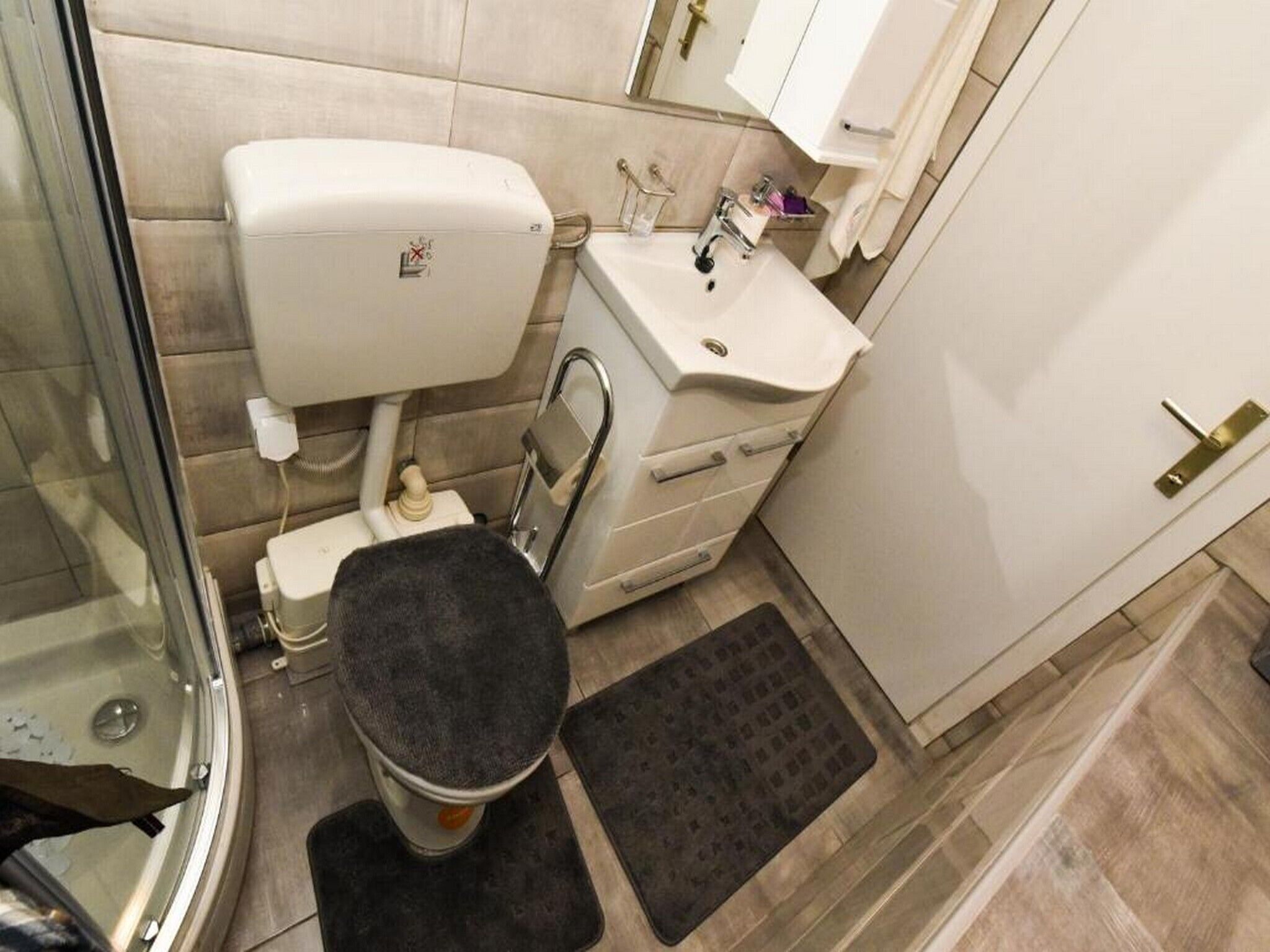 Une petite salle de bain comprenant des toilettes, un lavabo et un espace douche.