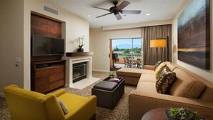 A modern living room with a flat-screen TV, a fireplace, a sofa, a yellow armchair, and a balcony with a view. - Westin Mission Hills (Rancho Mirage)