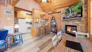 Un interior de cabaña acogedor con cocina, comedor y chimenea.