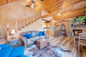 Un intérieur en bois comprenant un canapé, des fauteuils, une cheminée et un escalier.