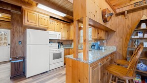 Una cocina con armarios de madera, un refrigerador blanco, un horno y una encimera de granito.