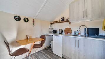 A compact kitchen with a wooden table, two chairs, a dishwasher, and a sink.