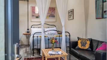 A bedroom with a bed, a bedside table with a book, a couch, and a decorative pillow.