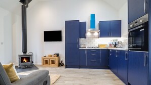 Eine moderne Küche mit blauen Schränken, einem eingebauten Herd und einem flachbildfernseher an der Wand.