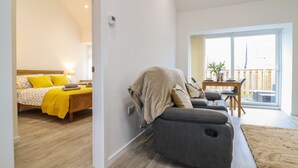 Ein modernes Wohnzimmer mit einer Couch, einem Essbereich mit Tisch und Stühlen sowie ein Schlafzimmer mit Bett und Nachttisch.