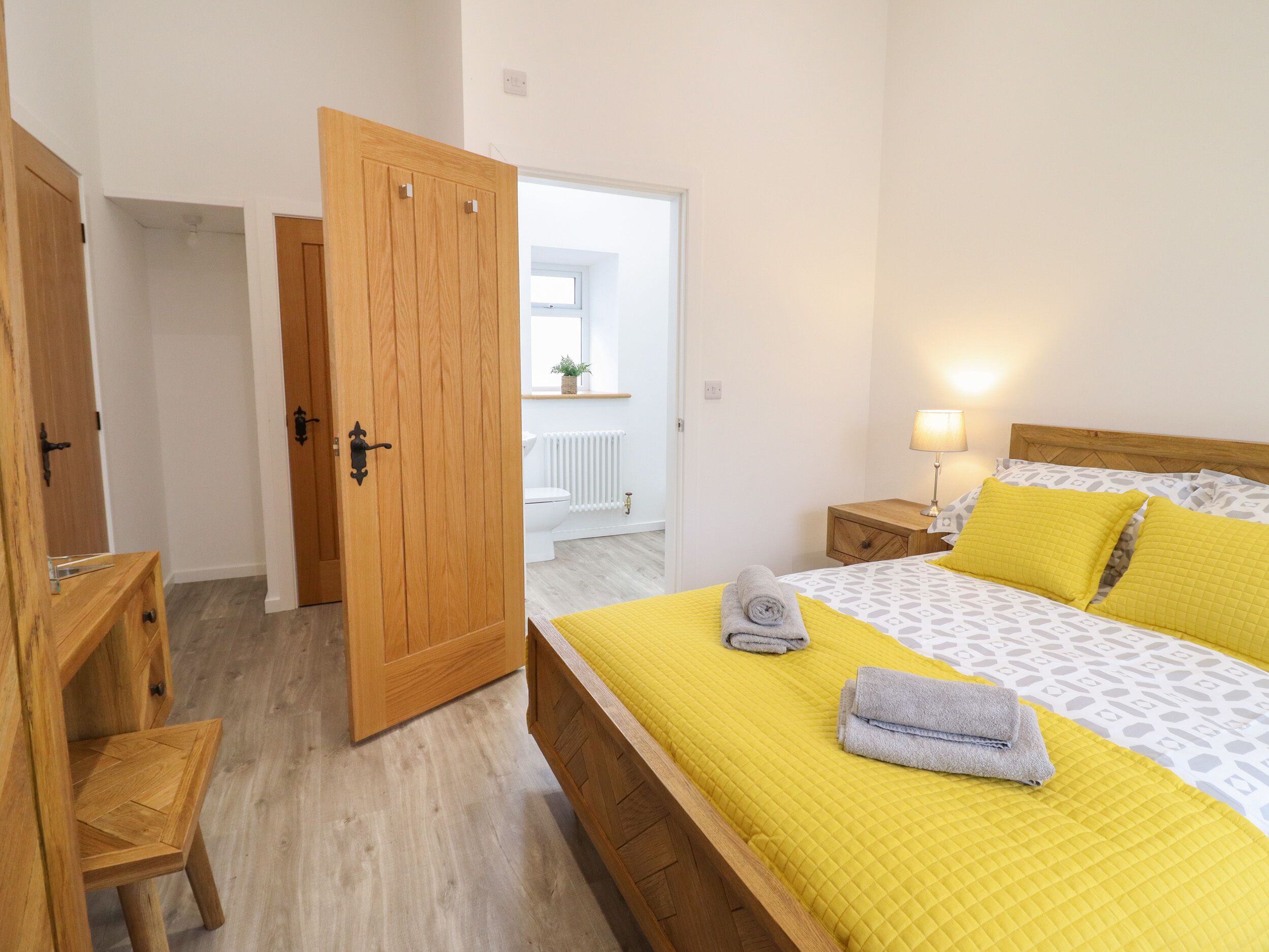 Un dormitorio con cama de madera, una mesita de noche, una silla y un armario de madera.