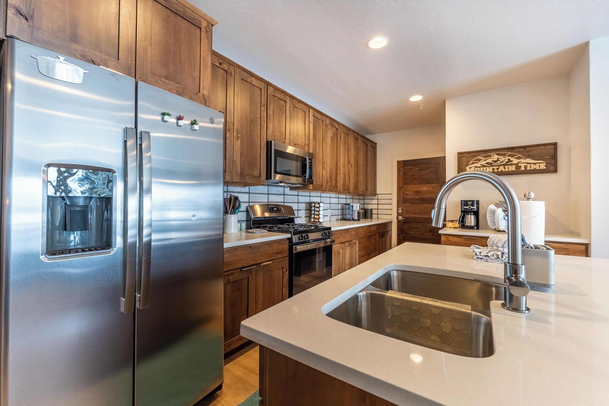 Una cocina moderna con electrodomésticos de acero inoxidable, armarios de madera y una isla grande con pileta.