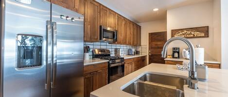 Una cocina moderna con electrodomésticos de acero inoxidable, armarios de madera y una isla grande con pileta.