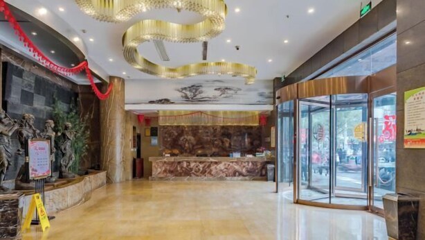 A hotel lobby with a marble reception desk, a glass entrance, and a ceiling with a circular light fixture. - Wancheng Hotel (Qianshan)