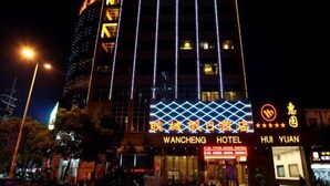 A hotel with a modern design, featuring a prominent sign for the Wancheng Hotel and a logo for Huiyuan. - Wancheng Hotel (Qianshan)